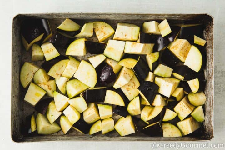 Raw eggplant cubes on a baking tray.