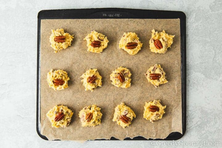 12 raw cookies on a baking sheet.