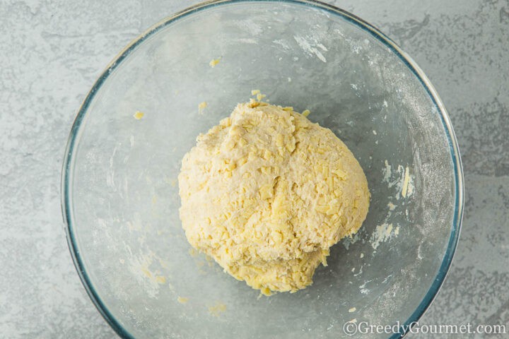 Cheesy cobbler dough ball in a glass bowl.