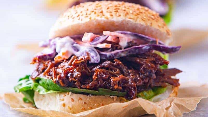 A pulled lamb slider on a seeded bun