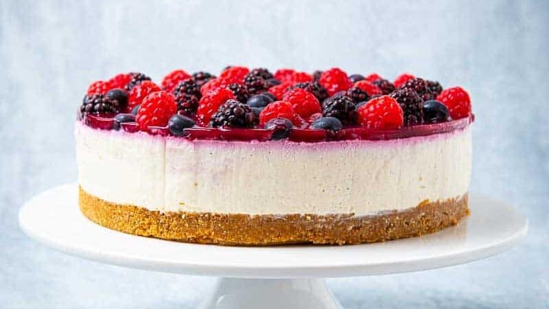Side view of a cheesecake with a fruit topping and a cracker crust
