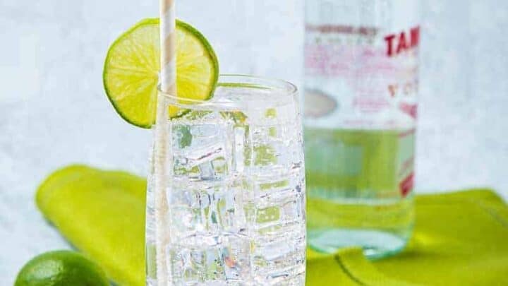Tall clear glass with a straw and bottle of vodka