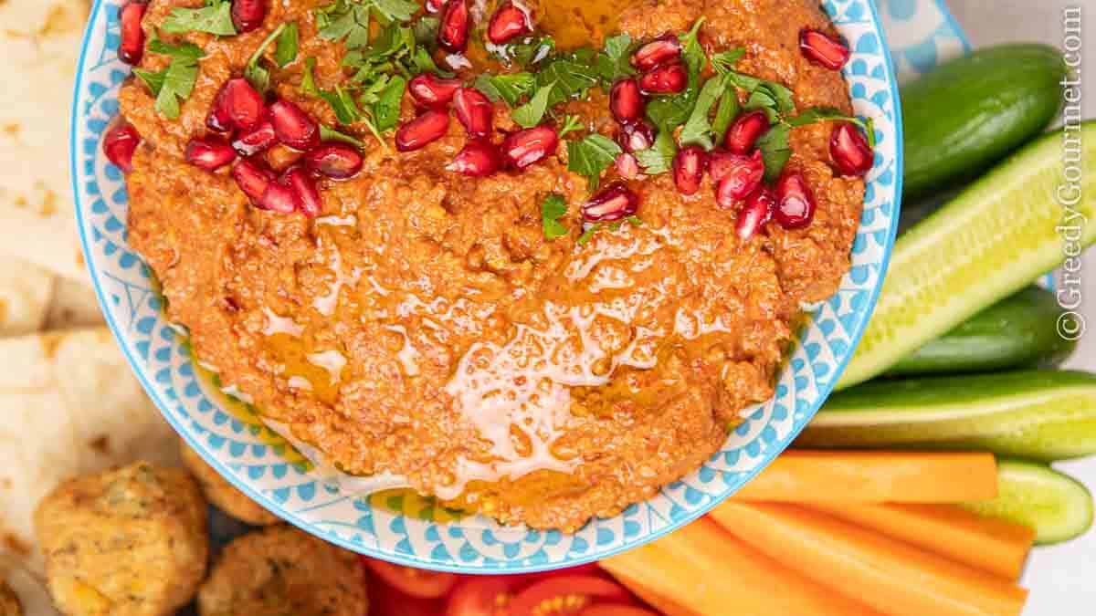 Bowl of bright orange muhammara (roasted red pepper dip)