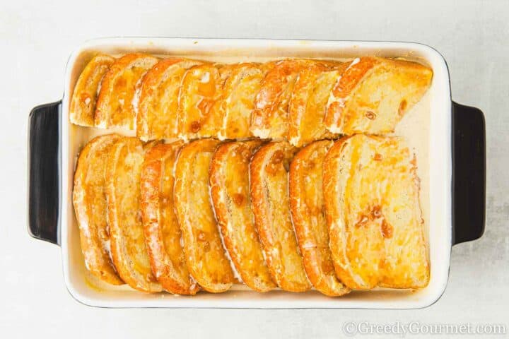 Soaking bread slices in custard om a dish.