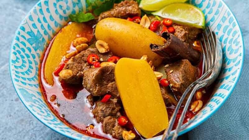 Close up of lamb curry and bowl of white rice