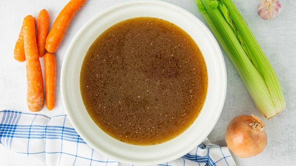 Bowl of turkey broth and fresh celery and carrots
