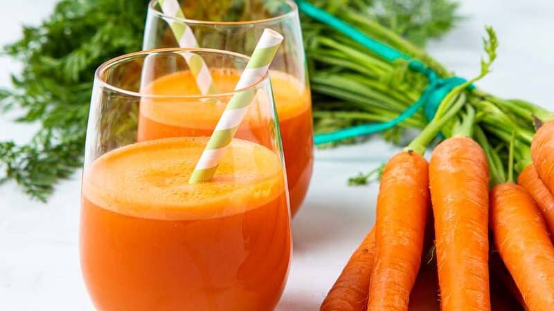 Two glasses of juice and fresh carrots