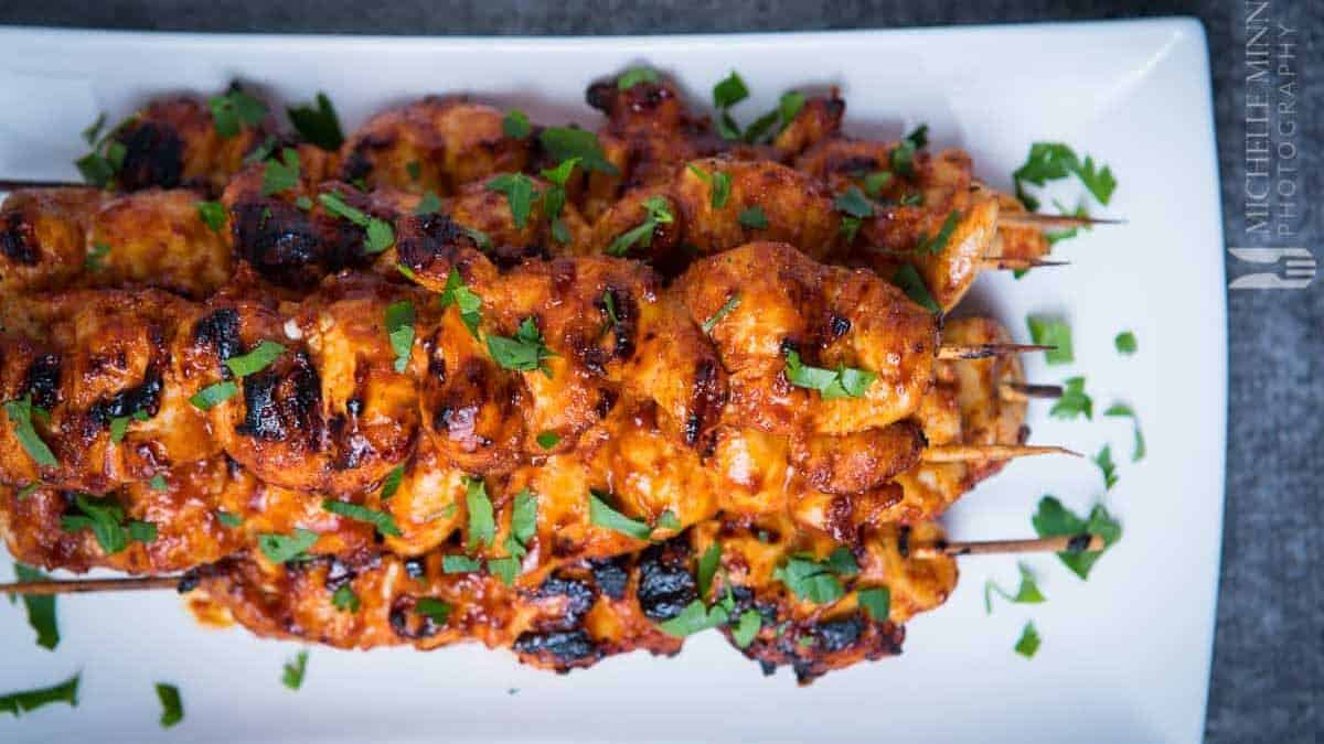BBQ Chicken Kebabs cooked on a white plate with parsley