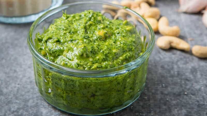 a bowl of green cashew pesto in a clear dish