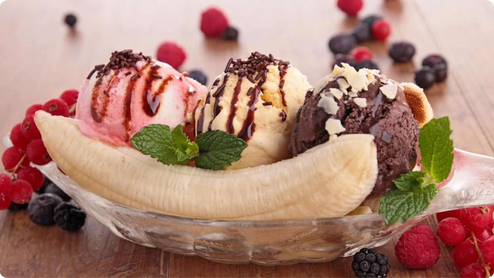 Fresh banana split serve in a fruit oval shaped bowl on a wooden table.