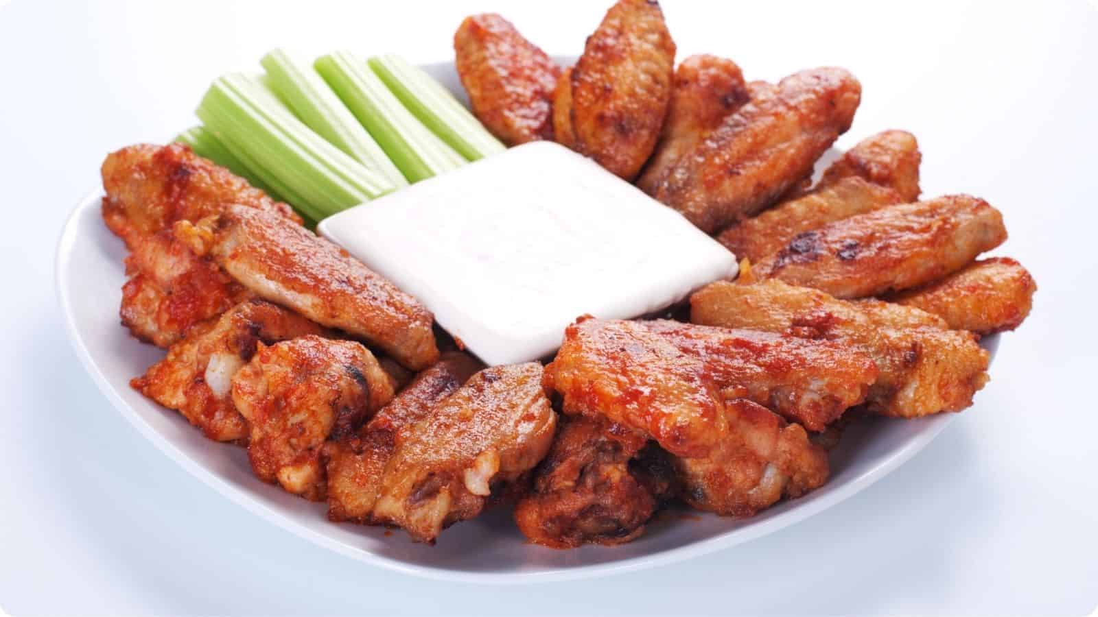Buffalo Wings arranged served in a white plate on countertop.