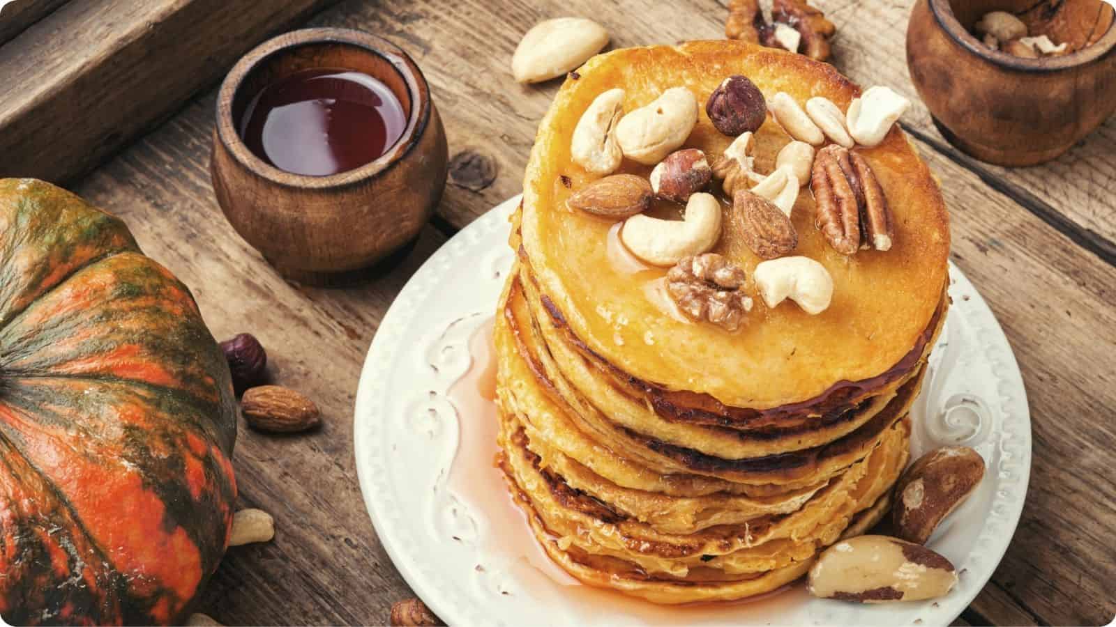 Stack pumpkin pancakes with honey and walnuts on top.