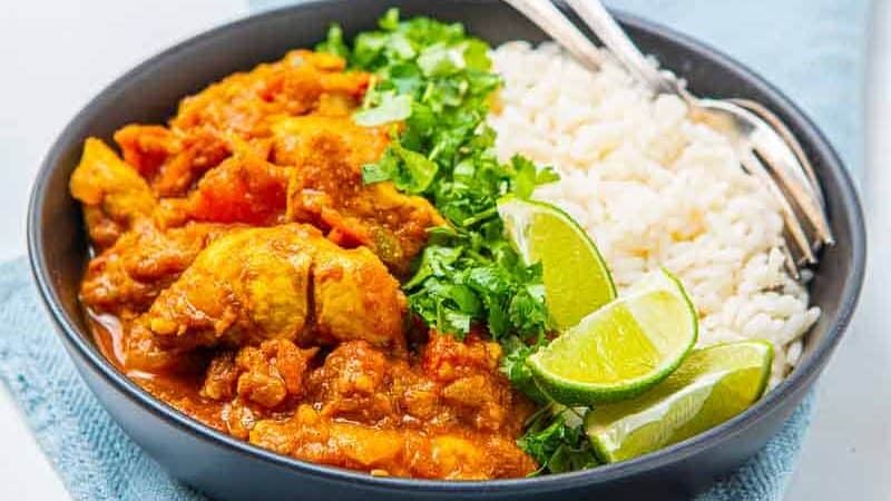 Bowl of chicken korai with white rice and limes in a bowl
