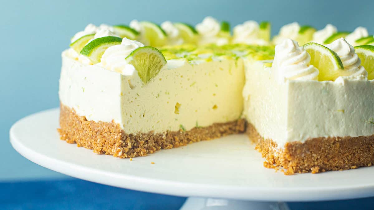 Round lime cheesecake with lime slices around the edges, served on a cake holder.