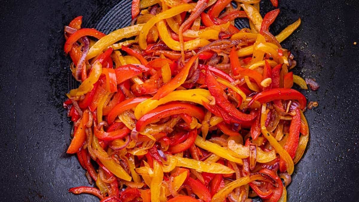 Close up of bright orange and red peppers and onions,