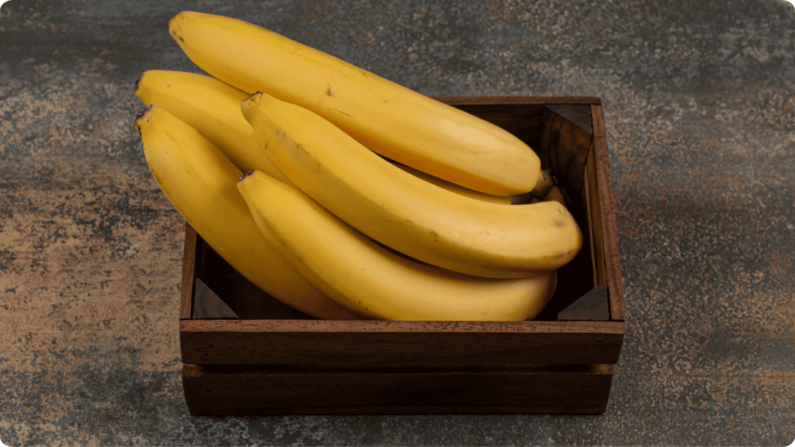 Bananas in a wooden box place on a table. 
