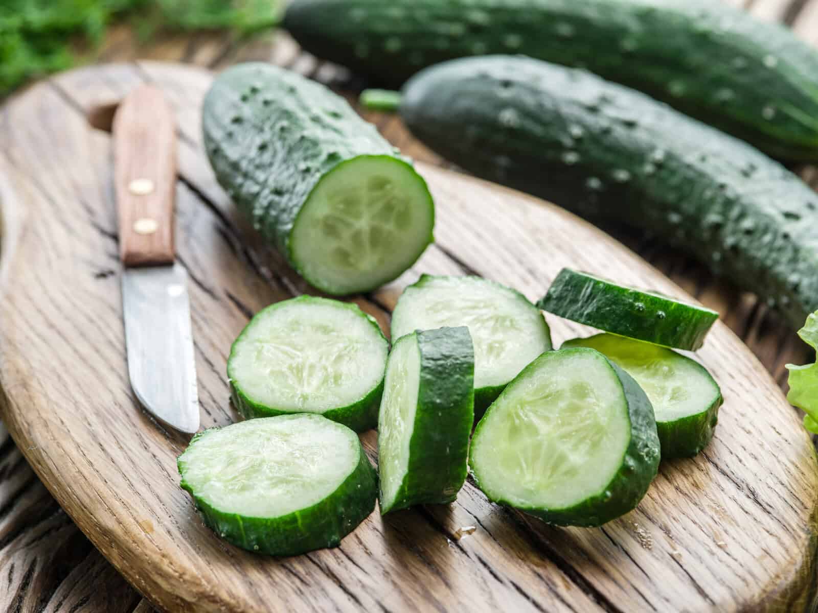 Slices of fresh cucumbers on top of a cutting board. 