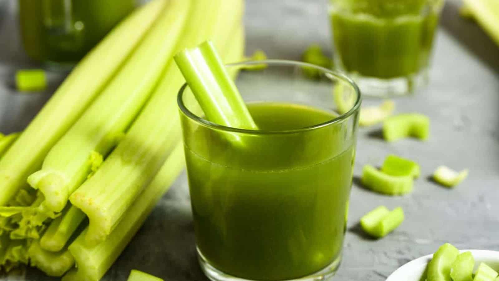 Celery sprigs and celery stick on celery smoothie displayed on a countertop. 