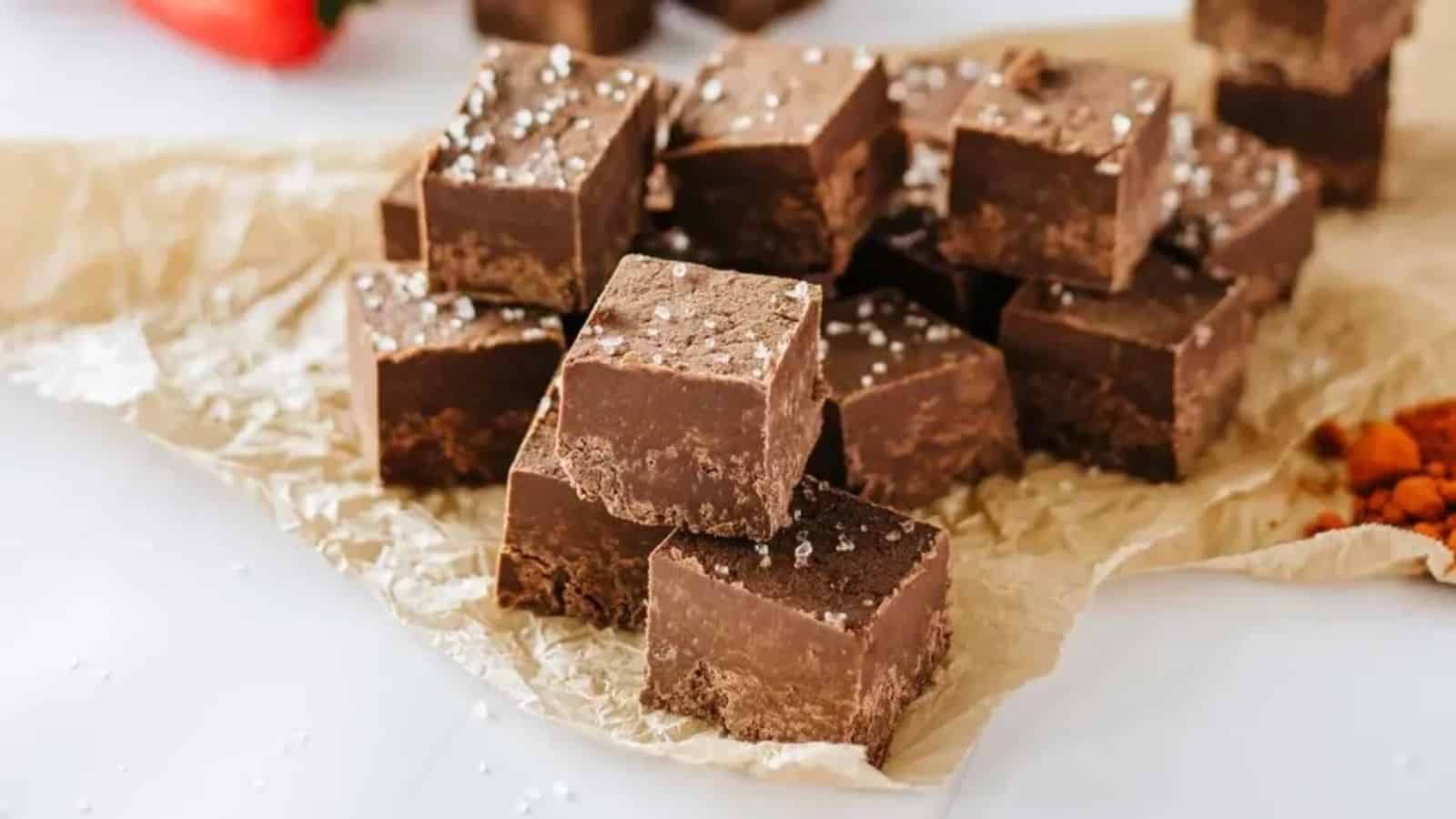 Chocolate slice in cubes sprinkled with sea salt over a white table. 