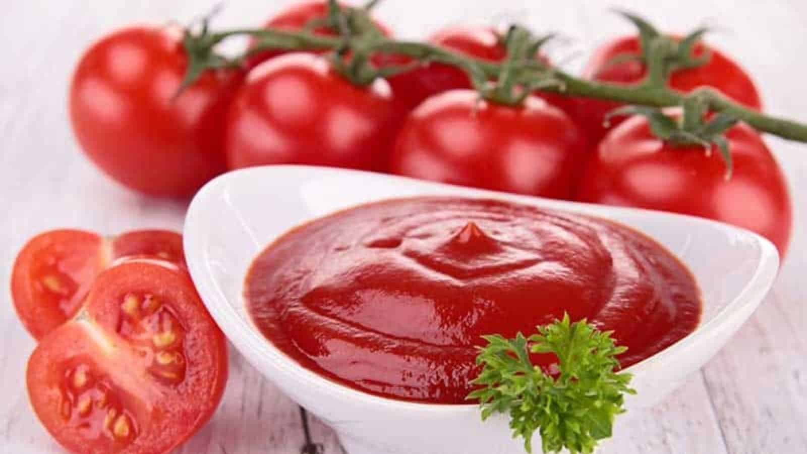 Tomato ketchup in a dip saucer with tomatoes on the side serve on the table.