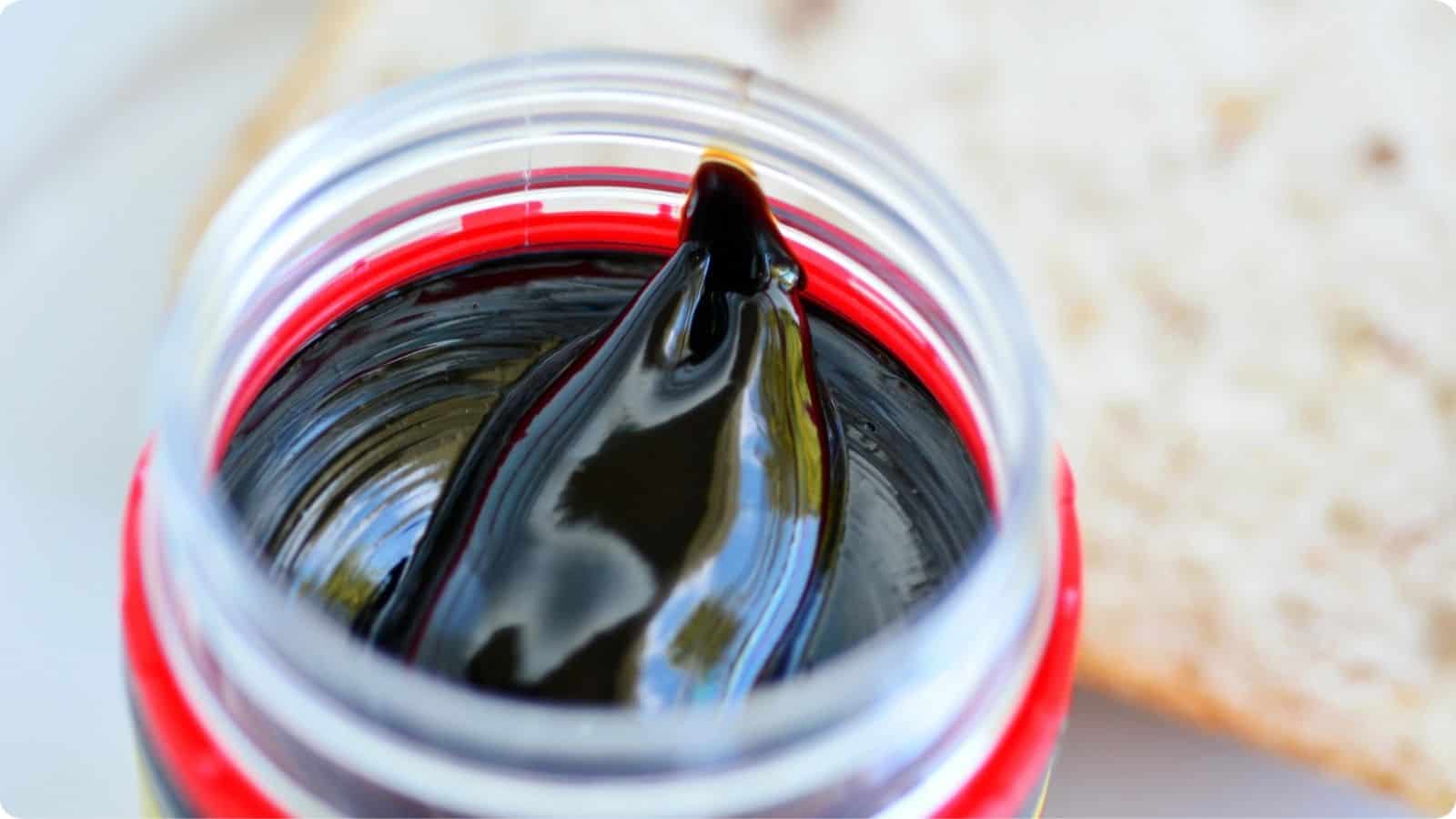 An open jar of Marmite is placed on a table.