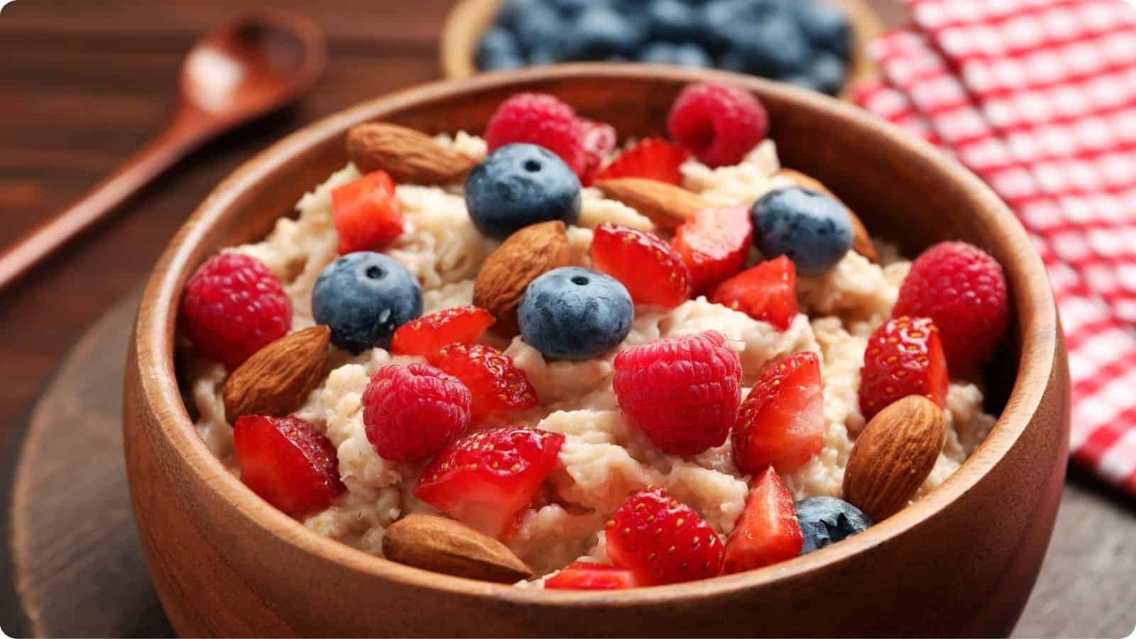 Clay pot bowl brimming with oatmeal, adorned with raspberries, walnuts, and blueberries, resting on a wooden surface.