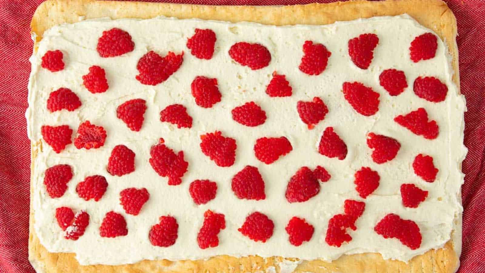 Raspberries filling spread on a raspberry pastry displayed on a cloth cover table. 