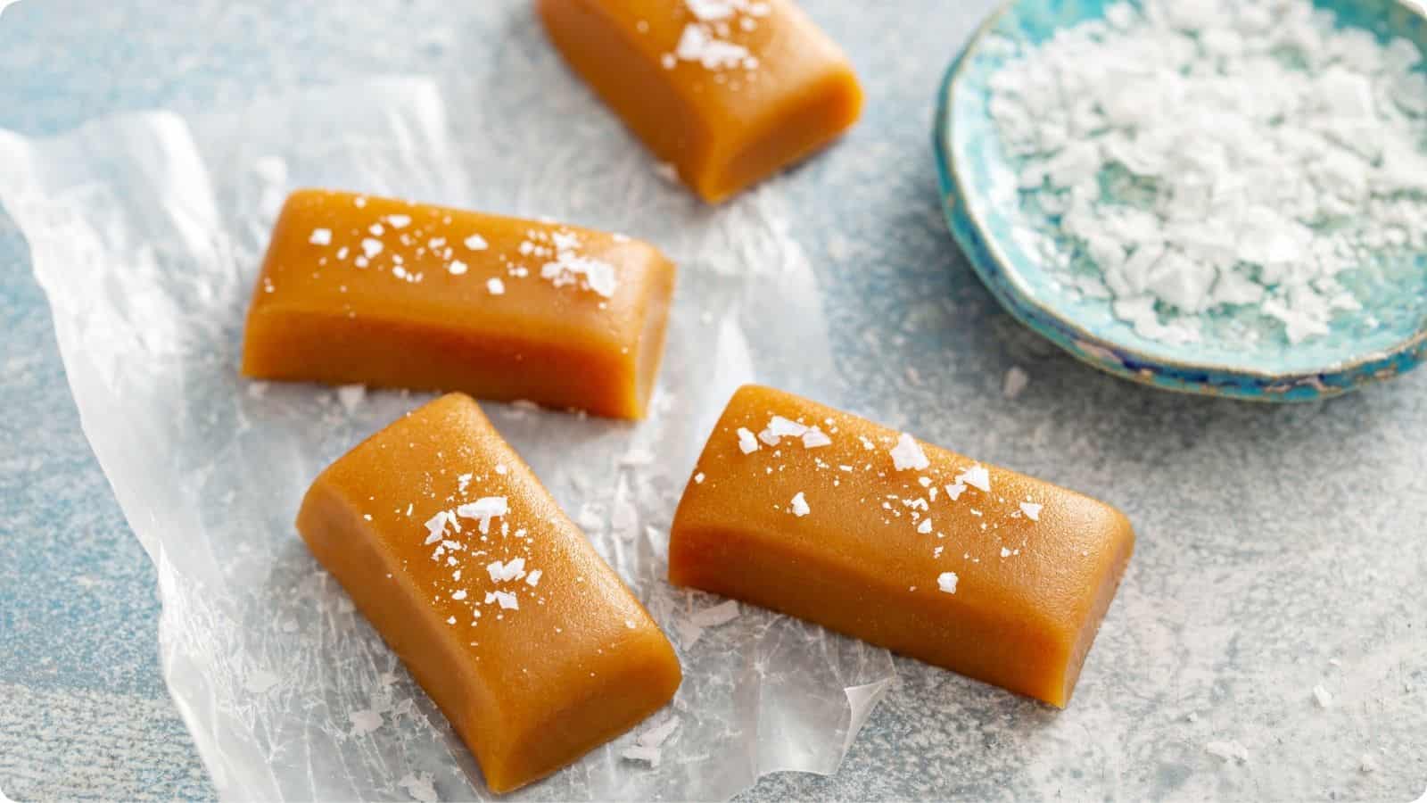 Caramel fudge candies with a sprinkle of sea salt, are displayed on a table.⁣⁣
⁣⁣⁣⁣⁣⁣⁣⁣⁣
