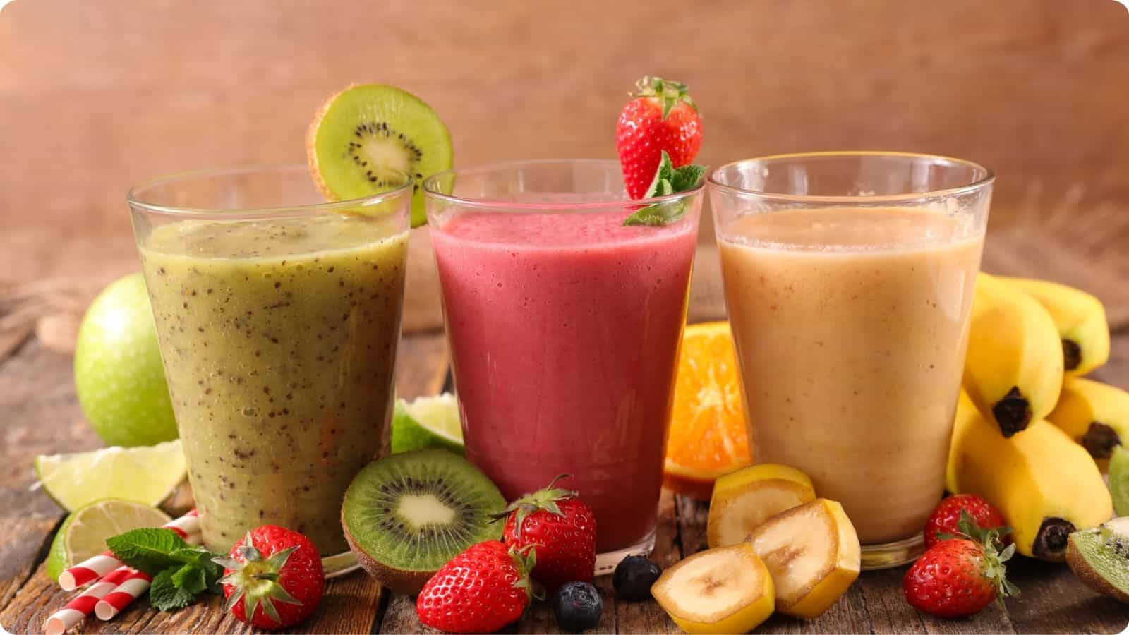 Glasses of smoothies flavored with kiwi, strawberry, and banana, presented on a wooden table