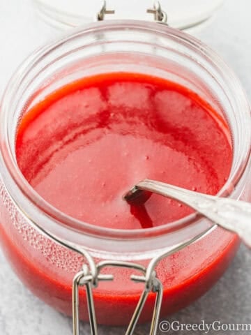 strawberry coulis in a glass jar.
