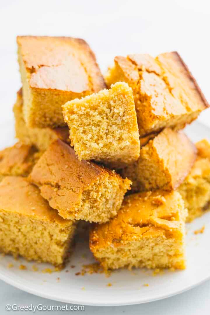 Cornbread slices in a pile on a white plate.