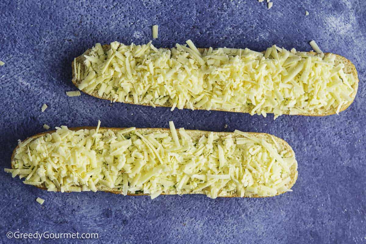 A baguette cut in half sideways with garlic butter and cheese.