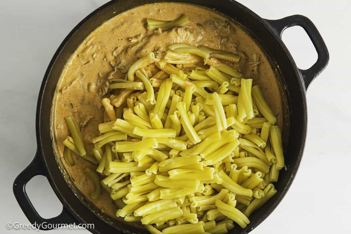 Adding pasta to cheese sauce.