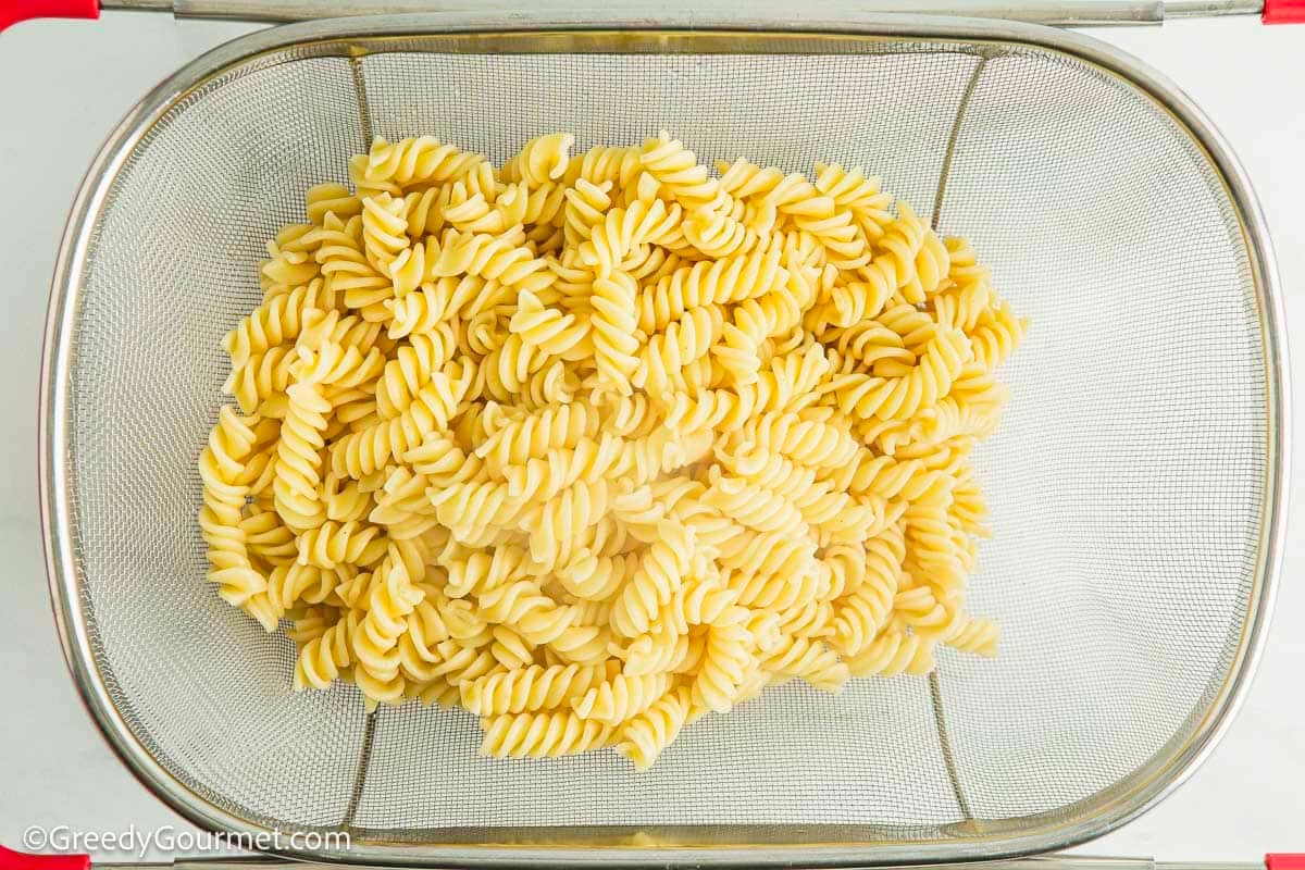 Cooked pasta being strained of water.