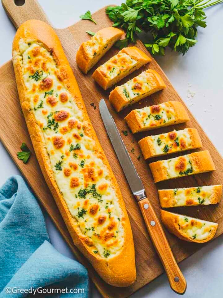 Cheesy garlic bread on a wooden board.