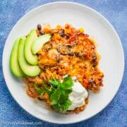Chicken Burrito Casserole on a plate served with sour cream and avocado.