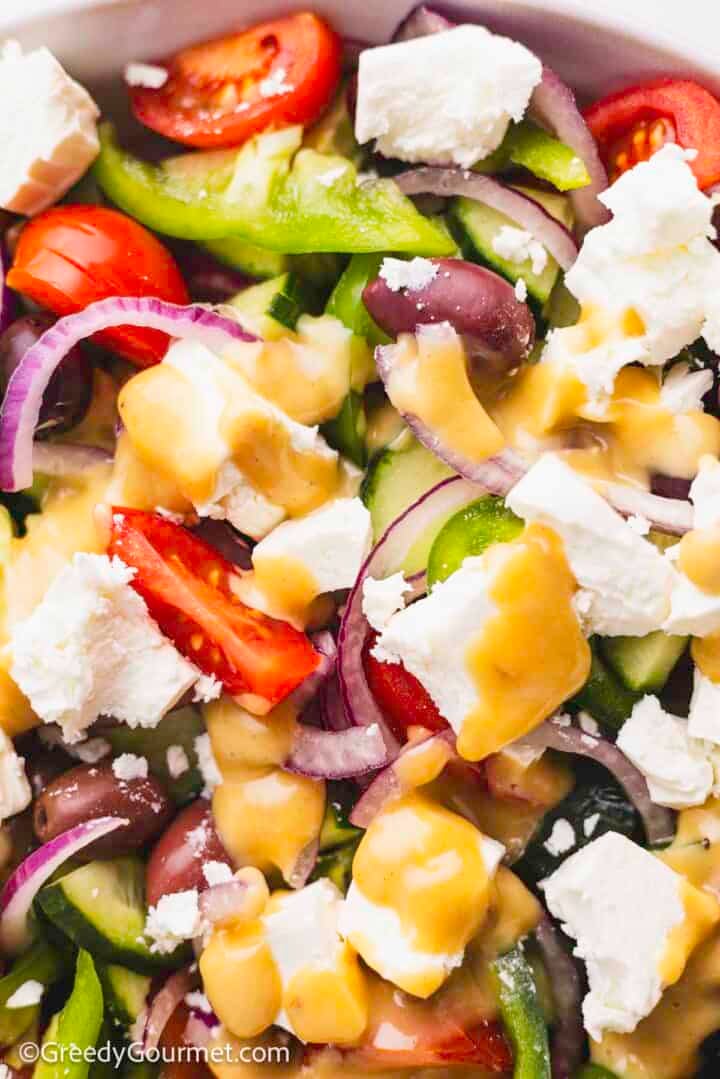 Close up of a Greek salad drizzled in a Greek salad dressing.