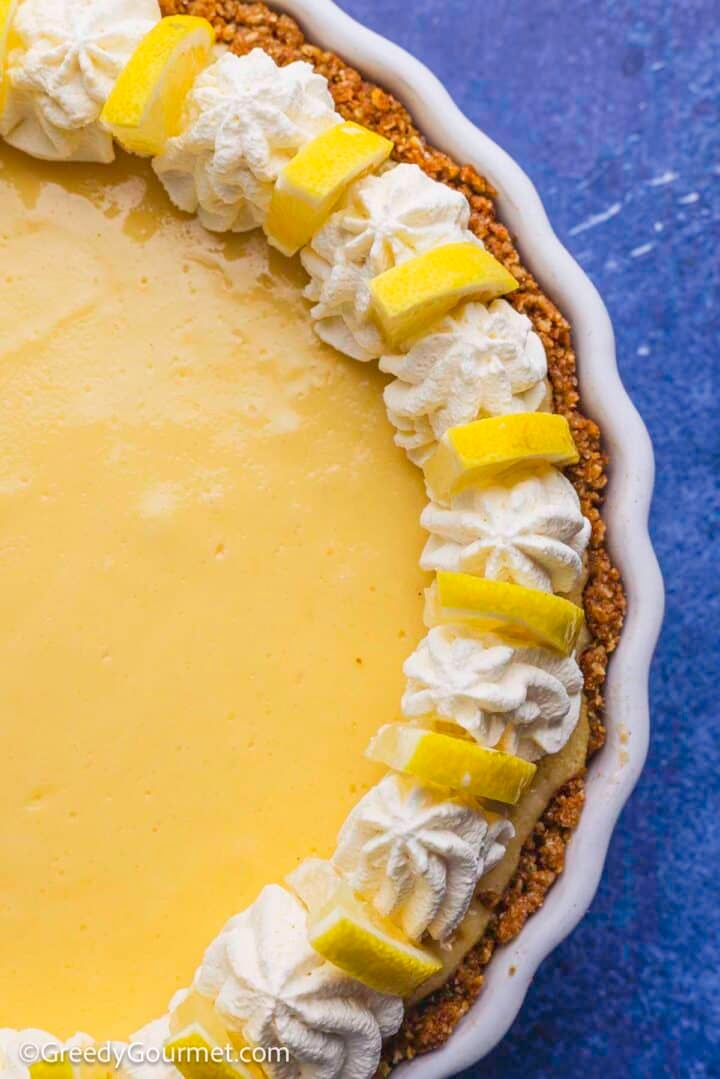 Lemon pie topped with whipped cream and lemon slices.