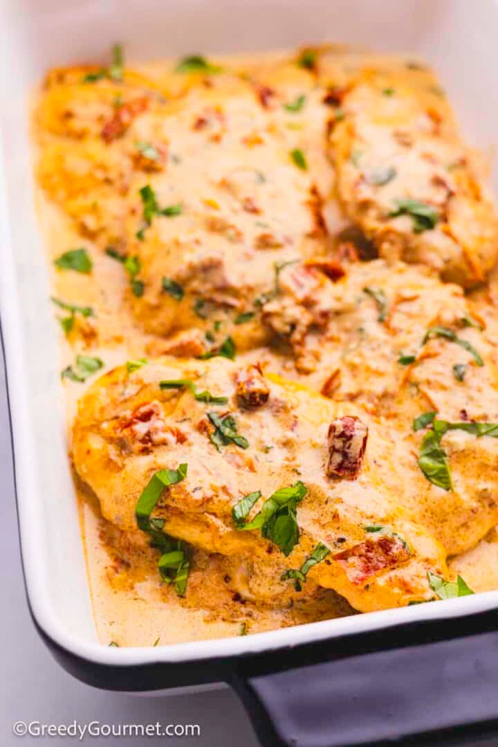 Cooked marry me chicken in a white baking dish.