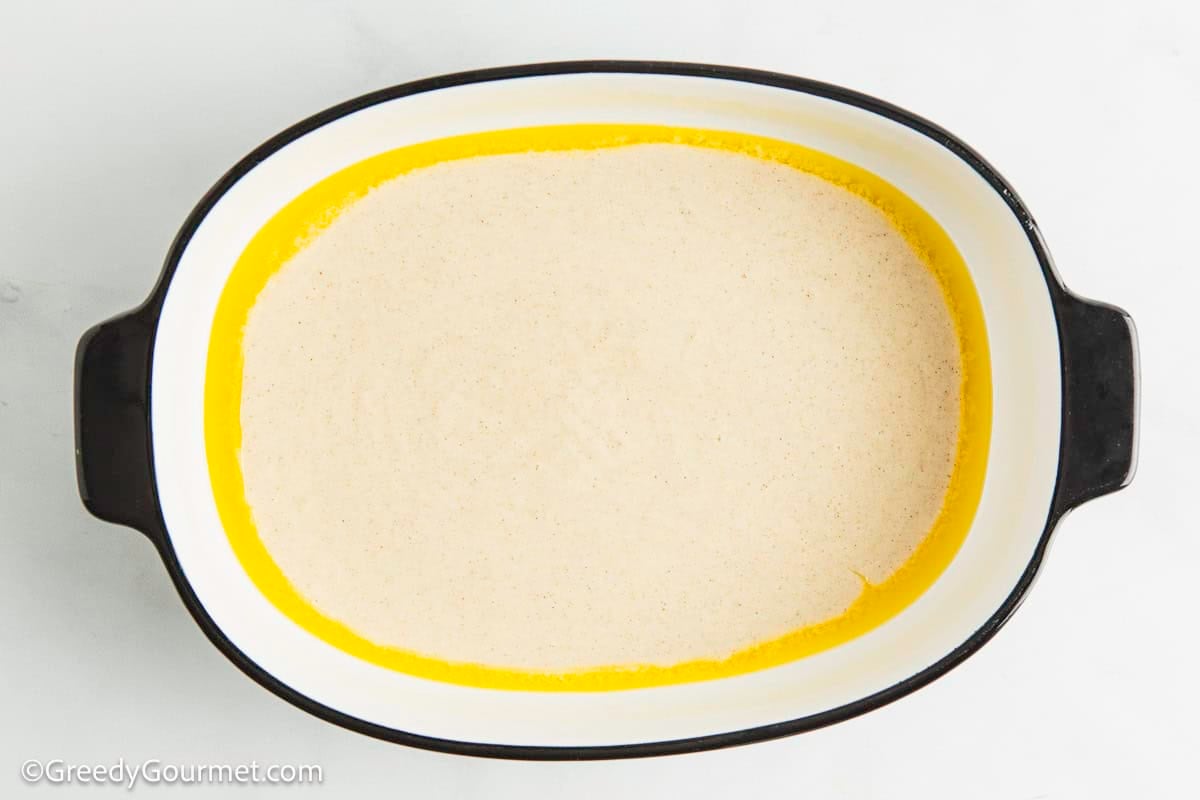 Melted butter and batter in a casserole dish.