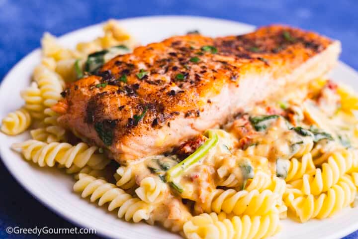 Marry me salmon on top of a plate of pasta.