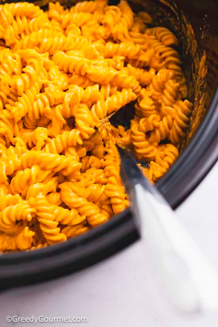 A slow cooker with cooked pasta and blended tomato and feta.